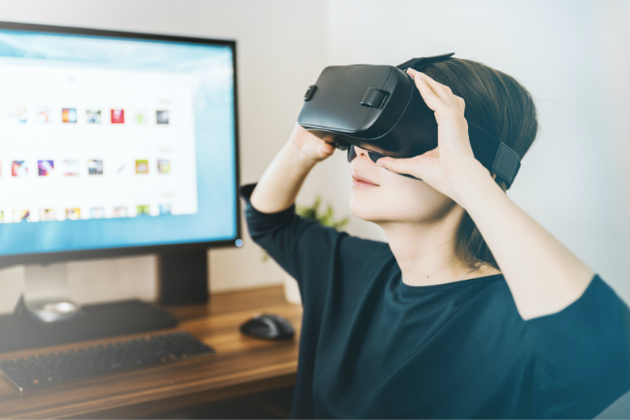 Young white girl sitting in front of a computer wearing black vr headsets while being part of a vr testing